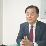 정장을 입은 한 남성이 책상 앞에서 손을 모은 채 인터뷰하듯 앉아 있는 모습으로, 새마을금고 관련 선거와 후보자 인터뷰 장면을 연상시키는 이미지.